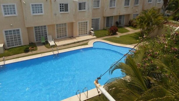 A swimming pool surrounded by a building with multiple balconies and windows. - Casa Familiar Acapulco Punta Diamante, Fracc. Puente del Mar, cerca de la playa. (Aeropuerto)
