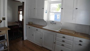 A kitchen with white cabinets, a wooden countertop, and a window. - Home located 2 blocks to the beach and Suttons Bay Village (Suttons Bay)