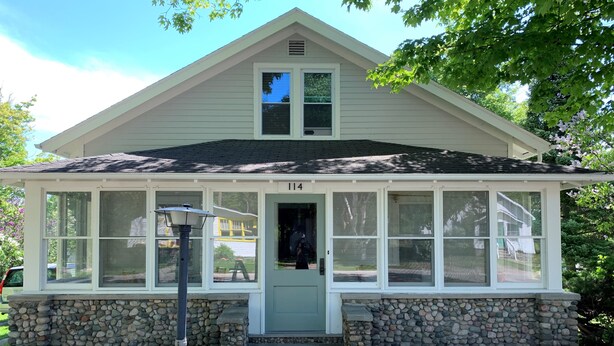 A house with a covered porch, stone foundation, and a number 114 on the door. - Home located 2 blocks to the beach and Suttons Bay Village (Suttons Bay)
