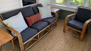 A room with a dark-colored sofa with striped pillows, a wicker chair, and a small wooden table. - Home located 2 blocks to the beach and Suttons Bay Village (Suttons Bay)