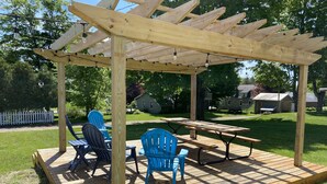 A wooden pergola with a picnic table and blue chairs in a backyard. - Home located 2 blocks to the beach and Suttons Bay Village (Suttons Bay)