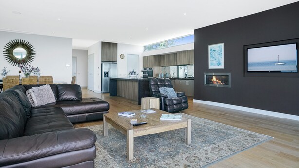 A modern living room with a leather sofa, a coffee table, and a fireplace. - Bayview Waterfront home Tyrone Foreshore (RYE)