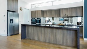 A modern kitchen with a central island, built-in ovens, and a stainless steel refrigerator. - Bayview Waterfront home Tyrone Foreshore (RYE)