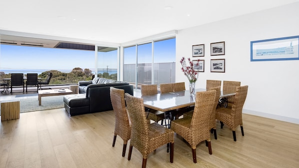 A modern dining area with a glass table and wicker chairs, overlooking a scenic view. - Bayview Waterfront home Tyrone Foreshore (RYE)