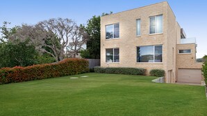 A modern two-story house with a well-maintained lawn and a wooden fence. - Bayview Waterfront home Tyrone Foreshore (RYE)