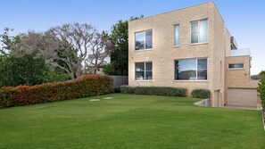 A modern two-story house with a well-maintained lawn and a wooden fence. - Bayview Waterfront home Tyrone Foreshore (RYE)