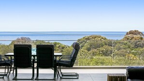 A balcony with a table and chairs overlooking a coastal landscape. - Bayview Waterfront home Tyrone Foreshore (RYE)