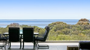 A balcony with a table and chairs overlooking a coastal landscape. - Bayview Waterfront home Tyrone Foreshore (RYE)
