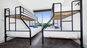 A room with two bunk beds, a window with a view of greenery, and a carpeted floor. - Bayview Waterfront home Tyrone Foreshore (RYE)