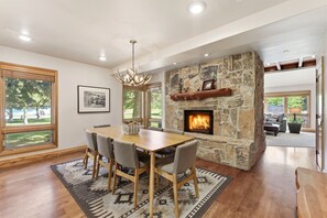 A dining area with a stone fireplace, wooden table, and chairs.