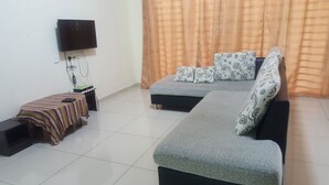 A living room with a sofa, a TV mounted on the wall, a small table with a patterned tablecloth, and a curtain. - NEWLINA HOMESTAY, Nibong Tebal, Seberang Perai Selatan, Penang, Malaysia. (Nibong Tebal)