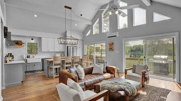 A spacious living area with a large leather sofa, a wooden coffee table, and a view of the backyard through large sliding glass doors.