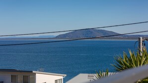 A coastal view with a mountain in the distance, a clear sky, and a building with a flat roof. - Spirit of Gerroa  - Moments from Seven Mile Beach (Gerroa)