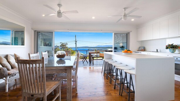 A modern kitchen with a large island, bar stools, and a view of the sea. - Spirit of Gerroa  - Moments from Seven Mile Beach (Gerroa)