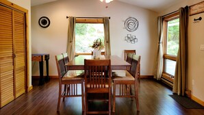 Un coin repas avec une table et des chaises en bois, un ventilateur de plafond et une fenêtre avec des rideaux.