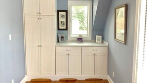 A room with a built-in white cabinet, a window with blinds, and a framed picture on the wall.