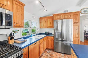 Cozinha moderna com armários de madeira, eletrodomésticos de aço inoxidável e bancada azul.
