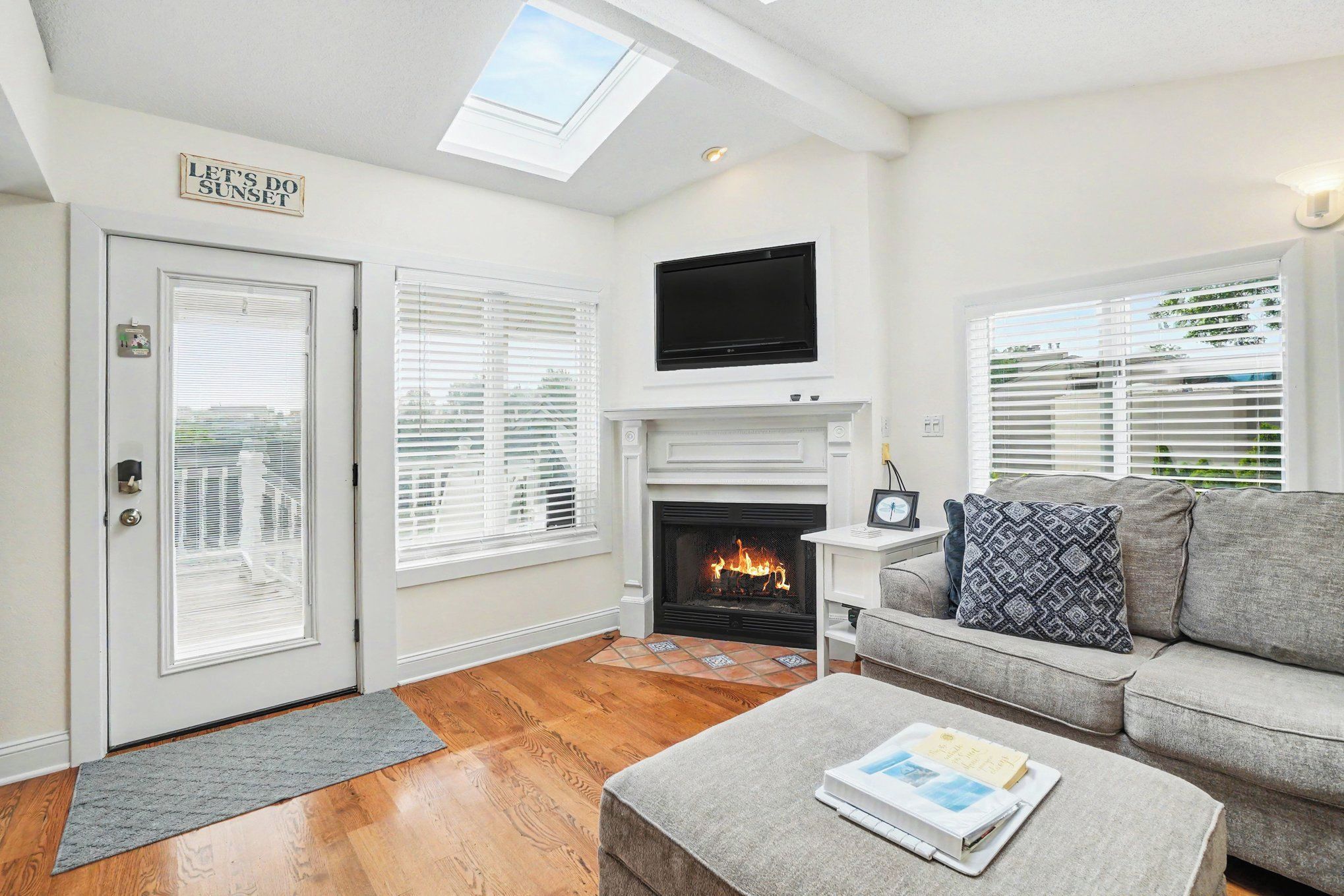 A living room with a fireplace, a sofa, a television, and a door with a sign.