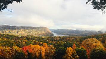 A panoramic view of a mountainous landscape with autumn foliage and a bridge in the distance.