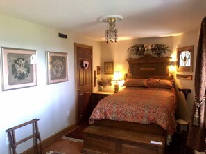 Una camera da letto con un letto in legno, un lampadario, opere d'arte incorniciate e un tavolino con una lampada.