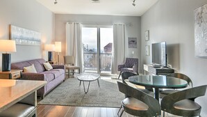 Un salon moderne avec un canapé, une table basse et des fauteuils, un balcon avec vue et un téléviseur à écran plat.
