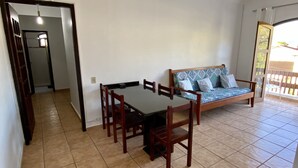 Een kamer met een eettafel en stoelen, een bank en uitzicht op buiten.