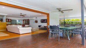 A spacious living area with a white sofa, a dining table with chairs, and a ceiling fan. - TROPICAL ESSENCE @ PALM COVE (PALM COVE)