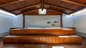 Un spa en bois doté d’une grande baignoire, d’escaliers en bois et d’un plafond agrémenté d’une lucarne.