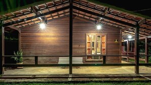 Una cabaña de madera con un porche cubierto, un banco y una puerta con paneles de vidrio.