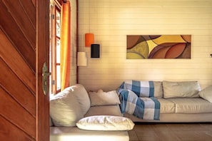 A cozy living room with a sofa, pillows, a blanket, and a wall-mounted abstract painting.