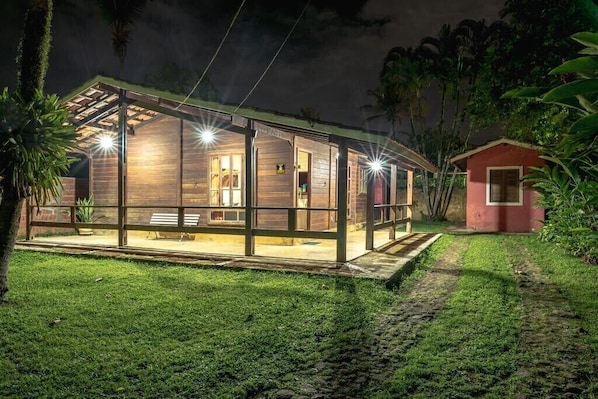 A modern house with a glass extension, a small red building, and a well-maintained lawn.