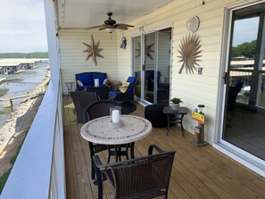 A covered outdoor area with wicker furniture, a table with a candle, and decorative star-shaped wall hangings. - Modern Style Condo! Amazing view!! (Osage Beach)