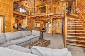 Relax in this inviting room with a comfortable sofa, wooden coffee table, and staircase to an upper level.