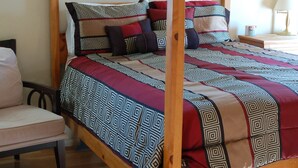 Un lit à baldaquin avec une couvre-lit à motifs, une tête de lit en bois et une table de chevet avec une lampe.