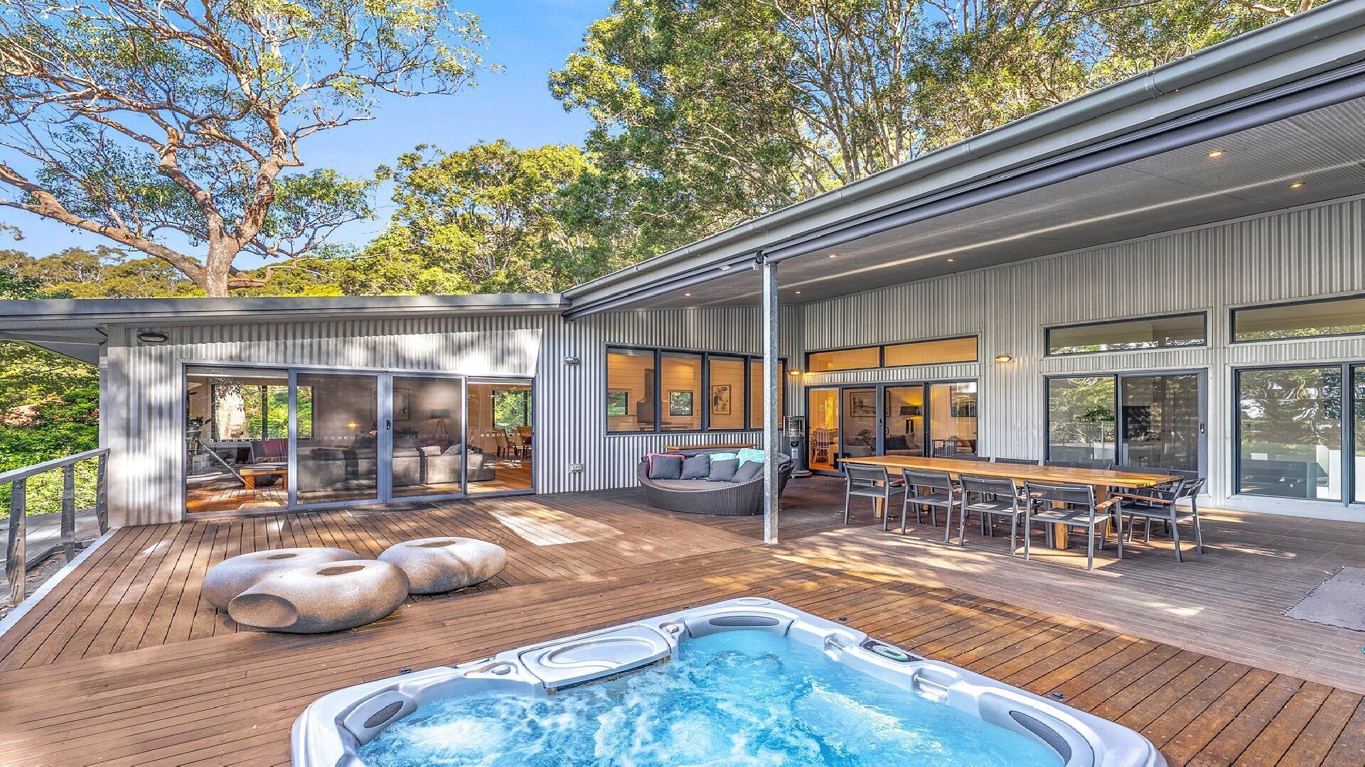 Una terraza moderna al aire libre con jacuzzi, zonas de estar y espacio para comer.