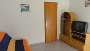Ein Zimmer mit einem Bett, einem Kleiderschrank, einem Fernseher auf einem Holzboden und einem gerahmten Bild an der Wand.