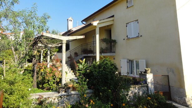 Ein zweistöckiges Haus mit Balkon, Treppe und Garten.
