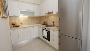 A modern kitchen with white cabinets, a stainless steel refrigerator, and a tiled backsplash. - Charming house with oversized heated pool (Baška Voda)