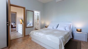 A bedroom with a bed, bedside tables, a dresser, a mirror, and an air conditioning unit. - Charming house with oversized heated pool (Baška Voda)