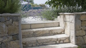 A stone staircase leading up to a terrace with a view of lavender bushes and a distant building. - Charming house with oversized heated pool (Baška Voda)