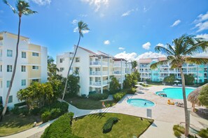 A resort with multiple swimming pools, palm trees, and a well-maintained lawn. - Playa Turquesa - B-302 -Premier Beachfront Ocean View 400mbps Wifi &Free Netflix (Punta Cana)