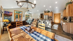 A spacious living area with a wooden dining table, a chandelier, and a fireplace. - Luxury Mountain Escape: BBQ, Forested, Balcony (South Lake Tahoe)