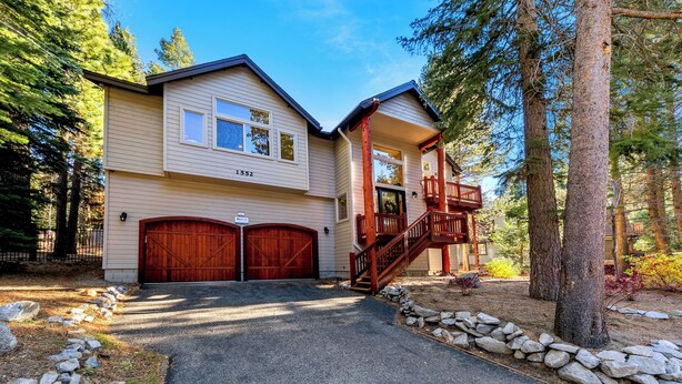 A two-story house with a garage, a wooden staircase, and a stone pathway leading to the entrance. - Luxury Mountain Escape: BBQ, Forested, Balcony (South Lake Tahoe)