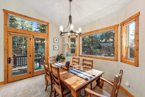 Uma sala de jantar com uma mesa de madeira, cadeiras e um lustre.
