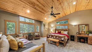 A spacious bedroom with a large bed, a wooden ceiling fan, and multiple windows providing natural light. - Luxury Mountain Escape: BBQ, Forested, Balcony (South Lake Tahoe)