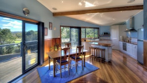 A spacious kitchen with a large island, wooden flooring, and a view of the outdoors. - Mayakitana - Freycinet Holiday Houses (Coles Bay)