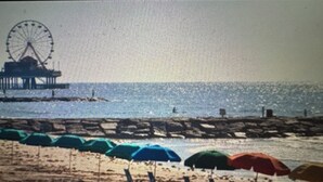 Ein Strand mit Sonnenschirmen und einem Steg.