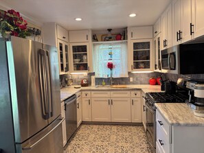 A kitchen with white cabinets, a stainless steel refrigerator, a stove, and a microwave.