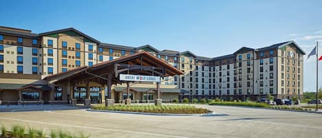 A multi-story hotel with a covered entrance, a flag, and a landscaped area in front.