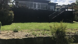 Ein modernes Haus mit einer großen Terrasse, einer Treppe und einem gepflegten Rasen.